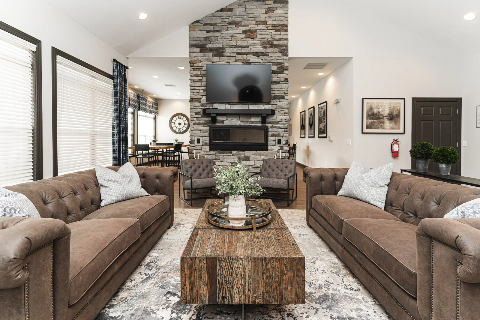 Commercial lounge with two tufted sofas, a wood coffee table, and a stone fireplace