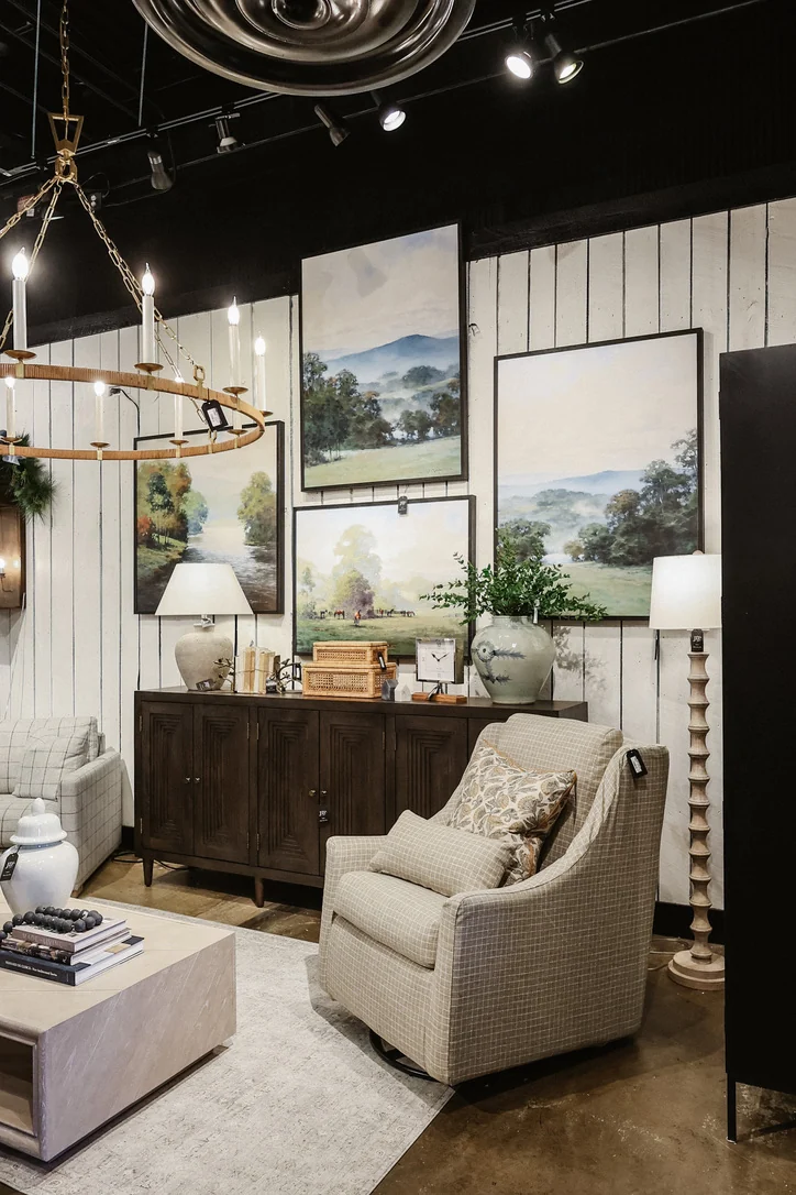 JD's showroom display with an upholstered chair, landscape artwork, lamps, and a wood cabinet