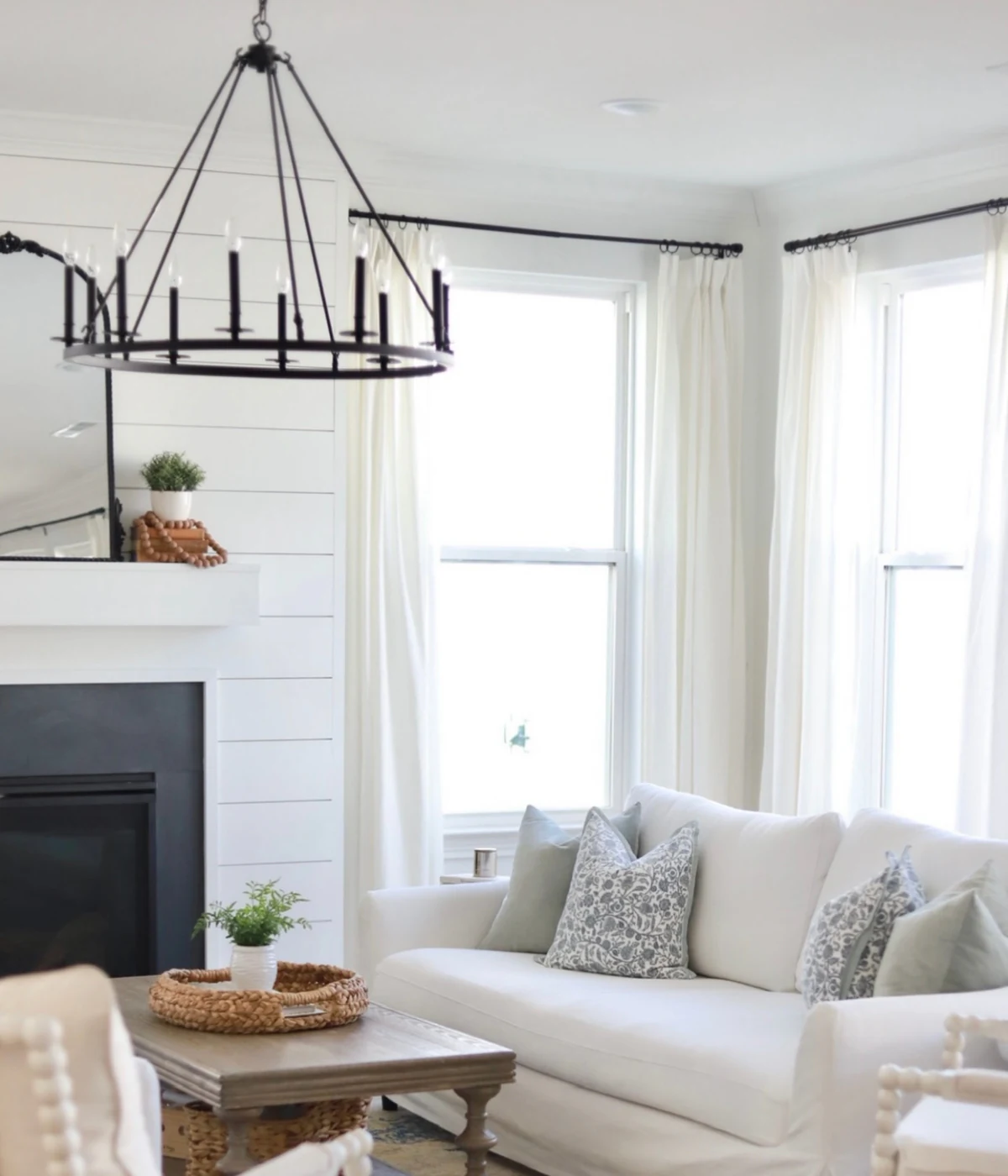 Completed living room with white seating, layered textiles, and tailored window panels