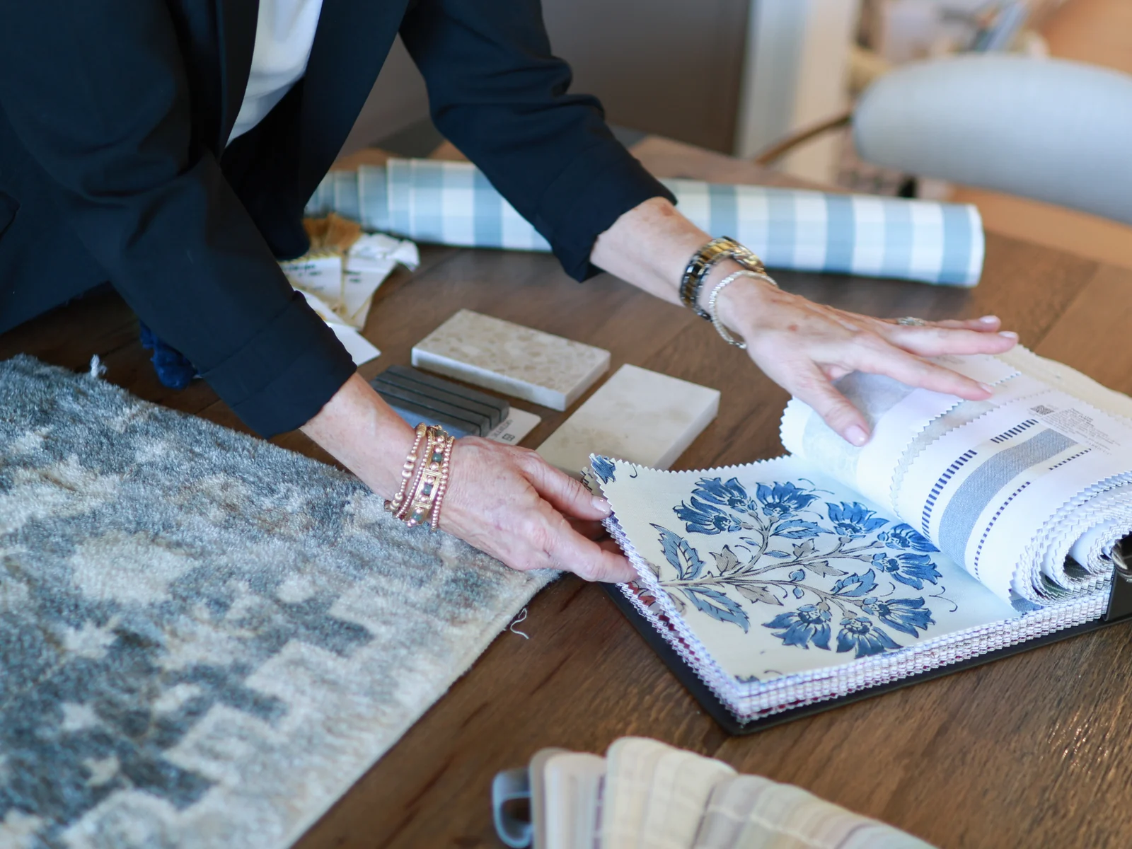 Hands compare coordinated textile samples and pattern books