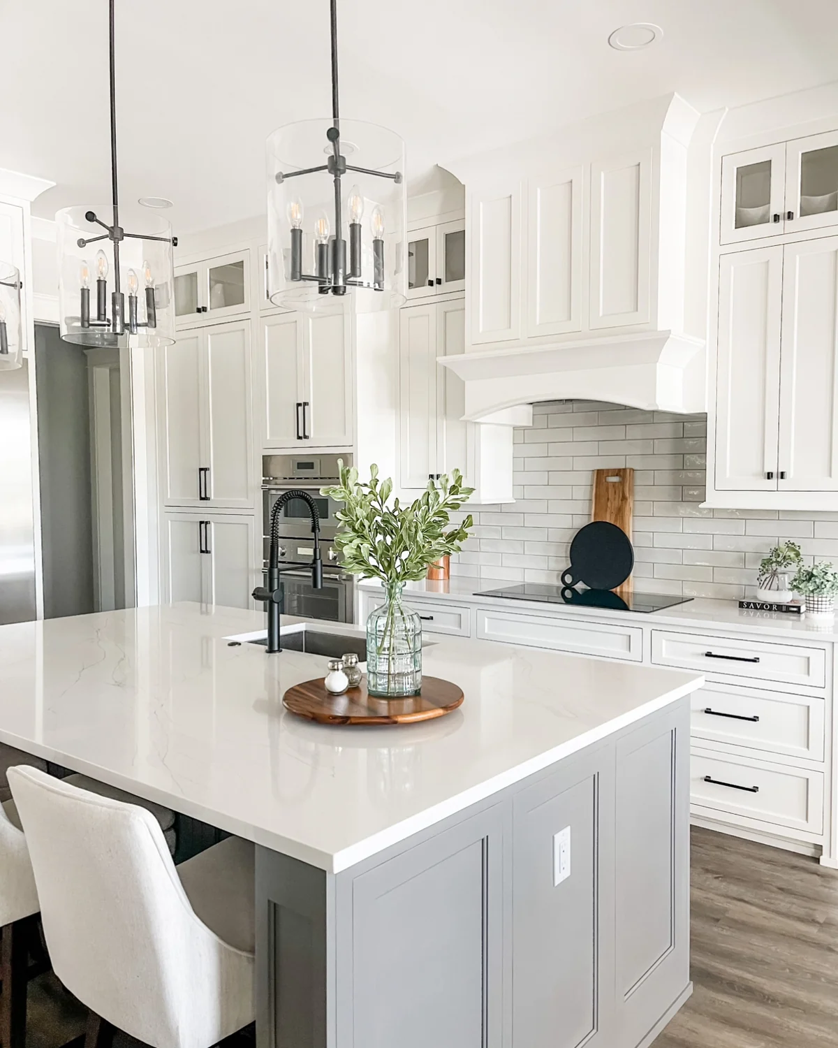 White kitchen with an island, pendant lighting, and a tiled backsplash