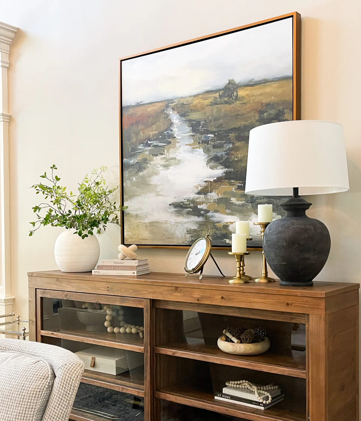 Collected console vignette with landscape art, lighting, greenery, and decorative objects