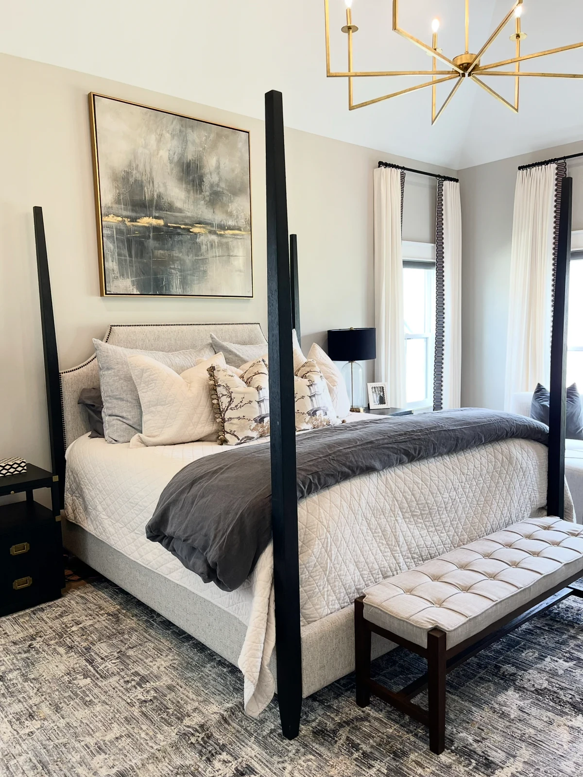 Completed bedroom with a four-poster bed, layered bedding, and tailored window panels
