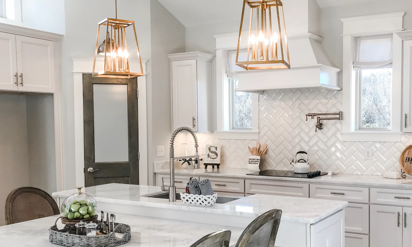 White kitchen with marble counters, a tiled backsplash, and gold pendant lighting