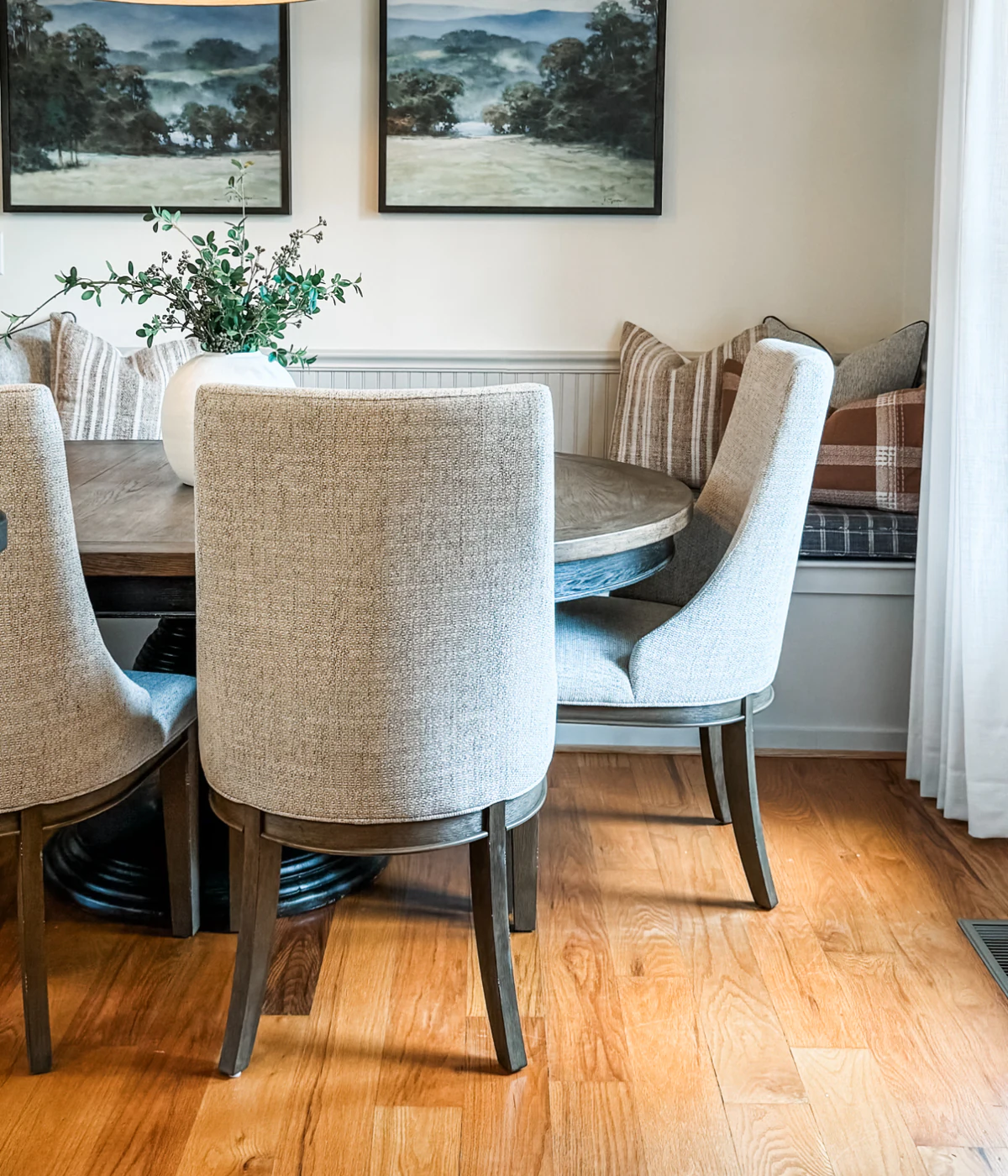 Completed dining nook with landscape art, upholstered chairs, and a built-in banquette