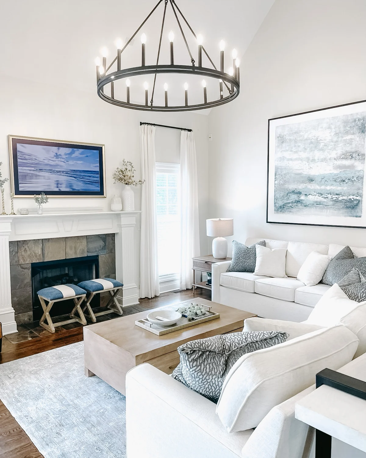 Bright living room with white seating, a fireplace, and a circular chandelier