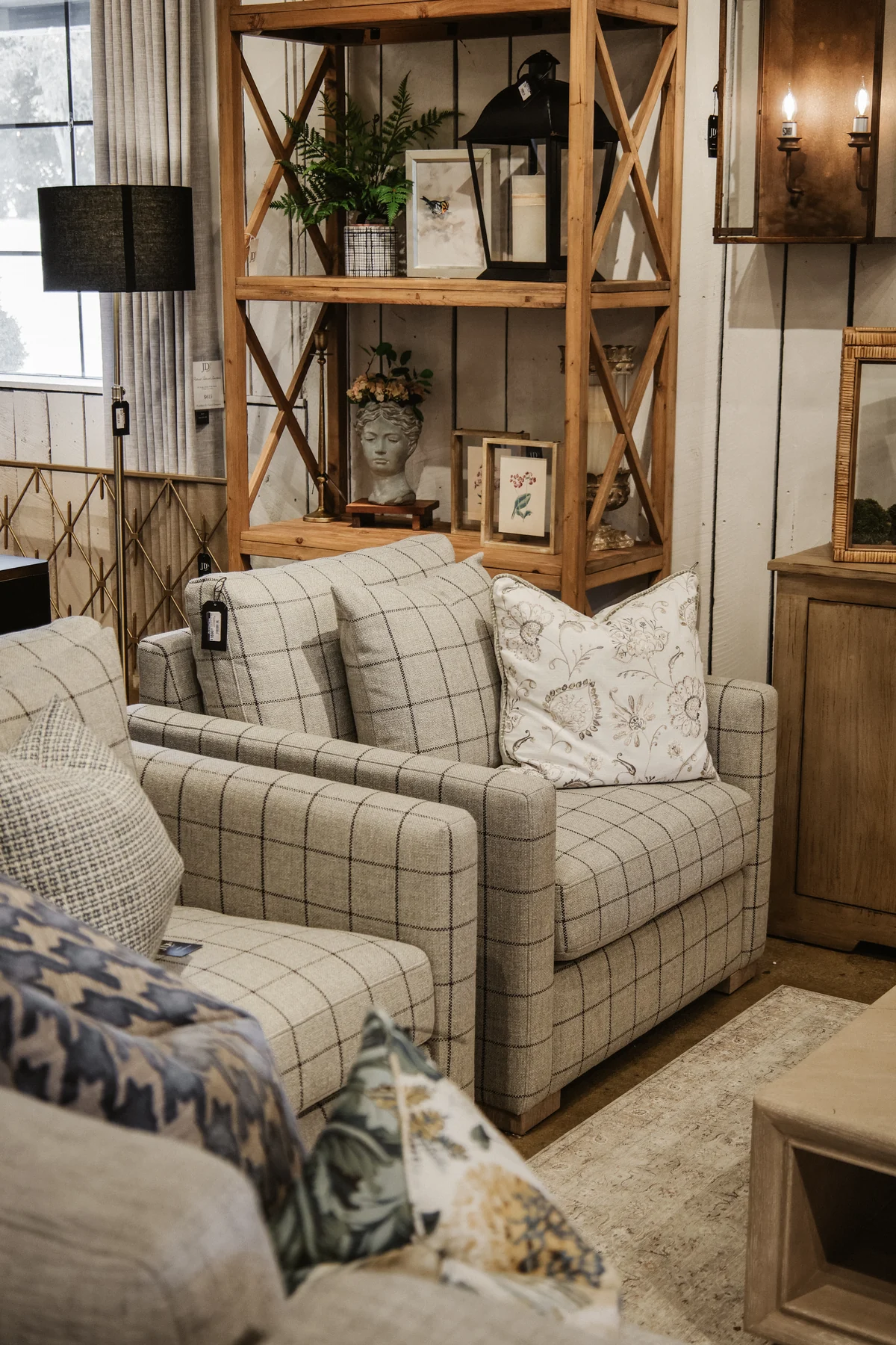 Plaid armchairs beside wood shelving, lamps, and accessories in the JD's showroom