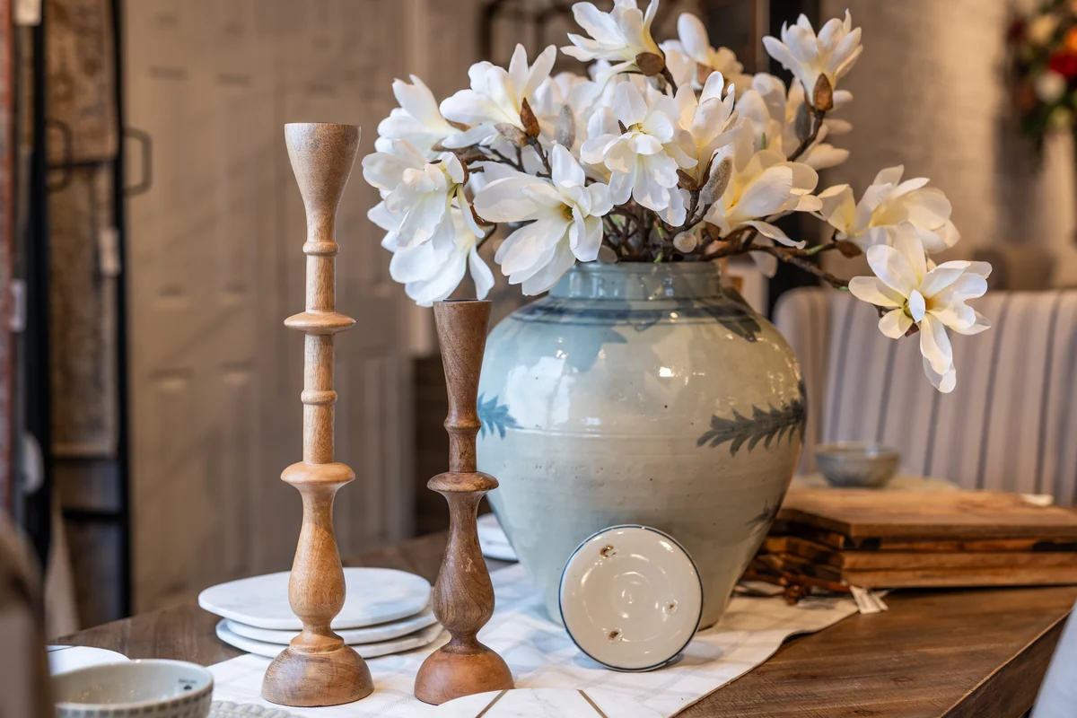 White flowers in a blue ceramic vase with candlesticks and decorative plates at JD's